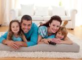 Family of four laying on foam mattress on top of clean white shag carpet