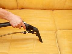 Hand steam cleaning yellow couch