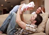 Dad holding up child on cleaned couch while mom watches