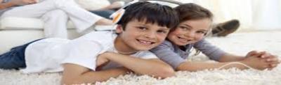 A boy and a girl laying on their stomachs on cleaned carpet