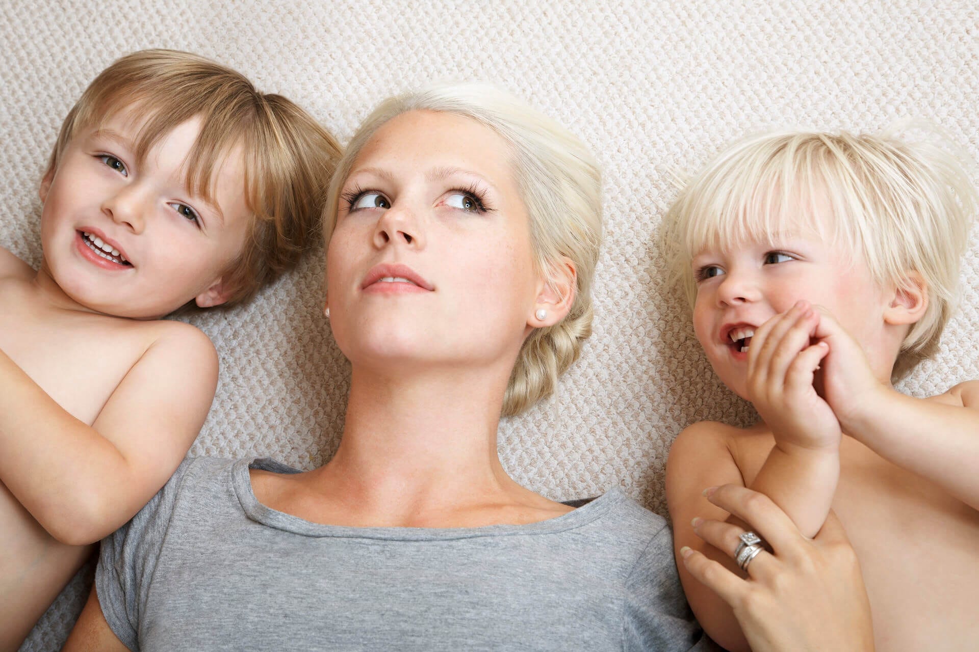 mom and 2 sons lying on clean carpet