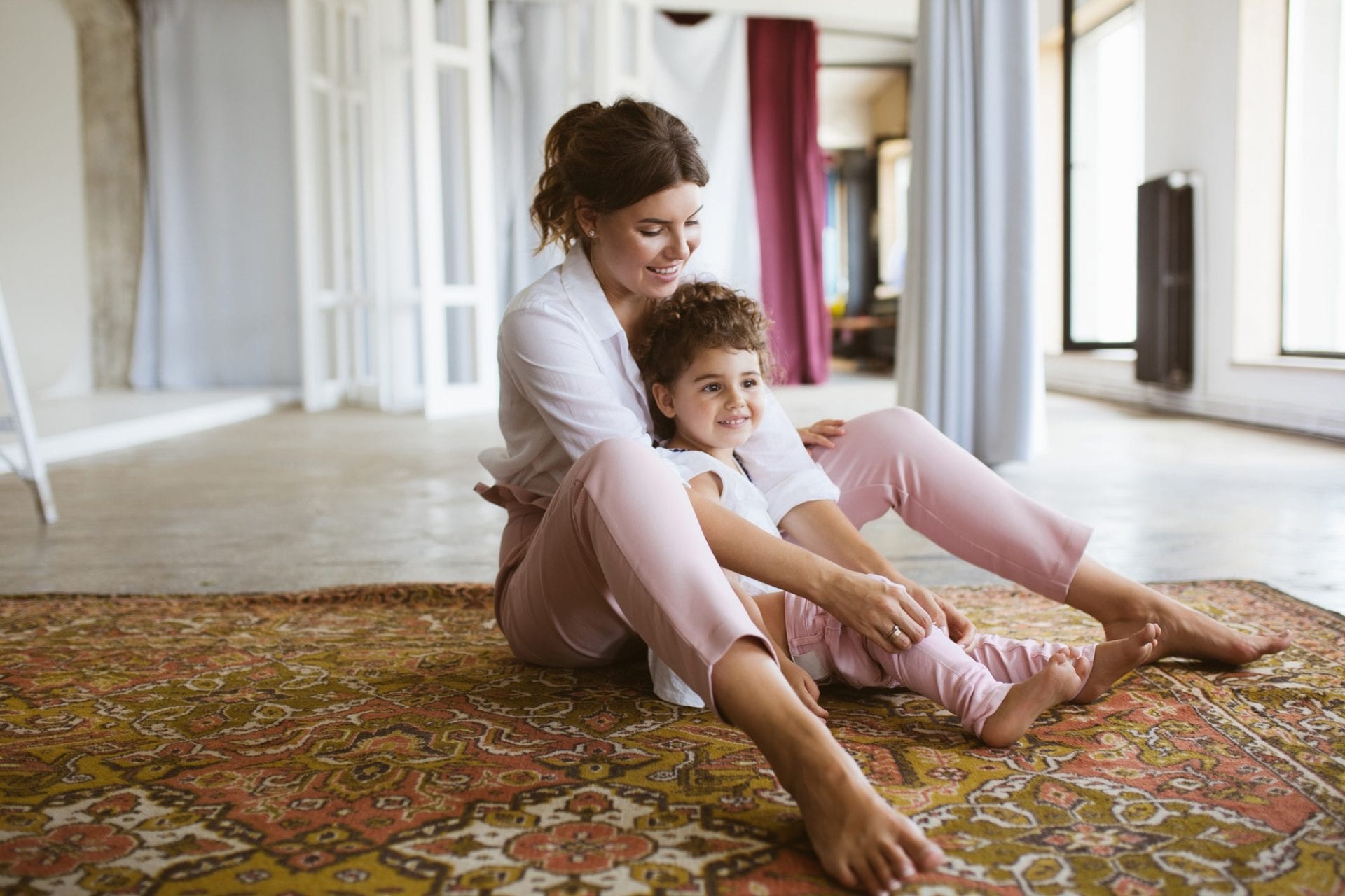 mom and daughter sitting on rug